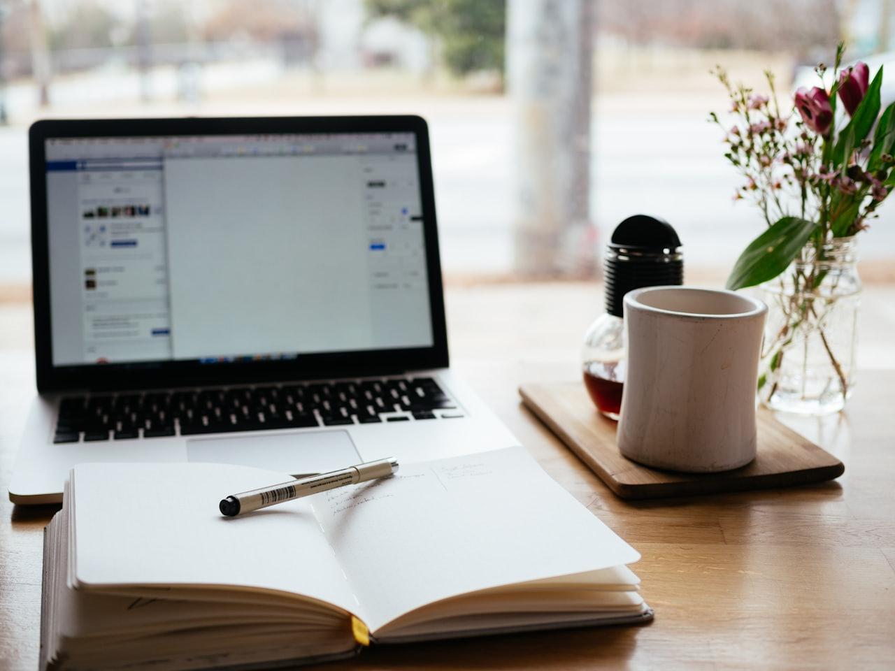 Laptop and open notebook on a desk in a bright learning space